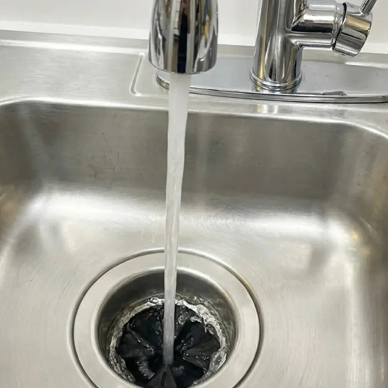 Water flowing from a faucet into a stainless steel sink rinsing the garbage disposal flaps